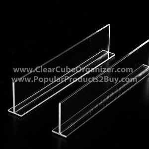 May include: Two clear acrylic shelf dividers, designed to create separate compartments within a shelf. The dividers are shaped like an upside-down 'T' and are made of sturdy, transparent acrylic.