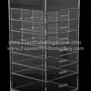 May include: Clear acrylic makeup organizer with 7 drawers. The organizer has a square base and is made of clear acrylic. The drawers are all the same size and are labeled with numbers.