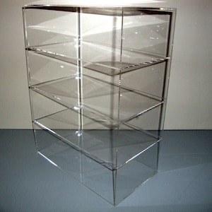 May include: A clear acrylic display case with four shelves. The case is empty and has a rectangular shape.