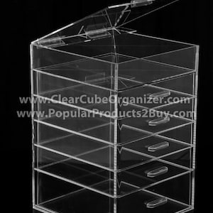 May include: Clear acrylic organizer with a lid and six drawers. The organizer is made of clear acrylic and has a modern design.