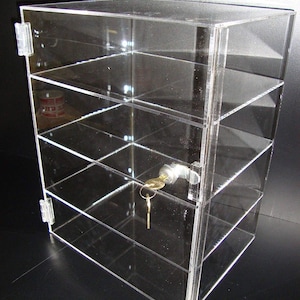 May include: A clear acrylic display case with four shelves and a lock with a key. The case is made of clear acrylic and has a modern design.