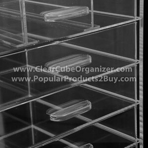 May include: Clear acrylic drawer organiser with multiple drawers. The drawers have clear plastic handles. The organiser is made of durable acrylic and is perfect for storing small items.