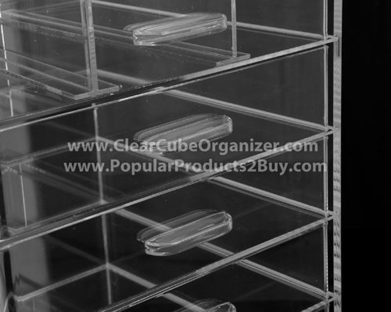 May include: Clear acrylic drawer organiser with multiple drawers. The drawers have clear plastic handles. The organiser is made of durable acrylic and is perfect for storing small items.