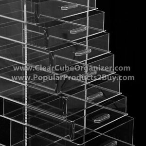 May include: A clear acrylic organiser with seven drawers. The drawers are stacked on top of each other and have a clear plastic handle on each drawer. The organiser is made of clear acrylic and has a sleek, modern design.
