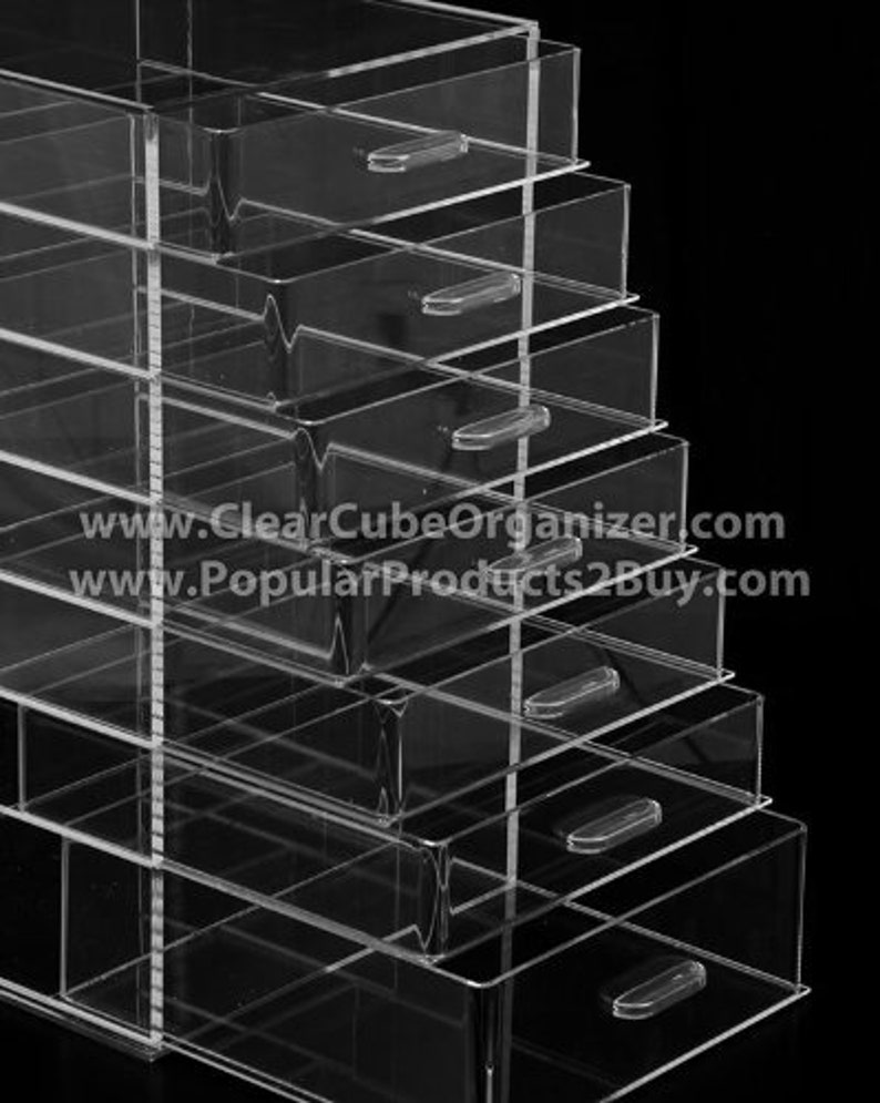 May include: A clear acrylic organiser with seven drawers. The drawers are stacked on top of each other and have a clear plastic handle on each drawer. The organiser is made of clear acrylic and has a sleek, modern design.