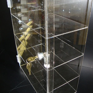 May include: Clear acrylic display case with a lock and key. The case has four shelves and is ideal for displaying small items.