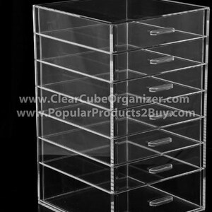 May include: Clear acrylic organizer with six drawers. The organizer is made of clear acrylic and has a modern design. It is perfect for storing small items such as jewelry, makeup, or office supplies.