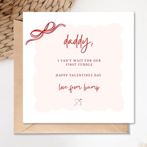 Puede incluir: Una tarjeta del Día de San Valentín con una ilustración de lazo rojo y el texto "papá, no puedo esperar nuestro primer abrazo, feliz Día de San Valentín, amor de bump". La tarjeta está en un sobre de papel kraft.