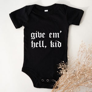May include: Black baby onesie with white text that reads "give em' hell, kid" in a gothic font.