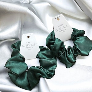 May include: Two green satin scrunchies with white tags that read "I can't tie the knot without you!"