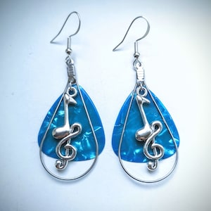 May include: A pair of silver earrings with a blue guitar pick design and a silver treble clef charm.