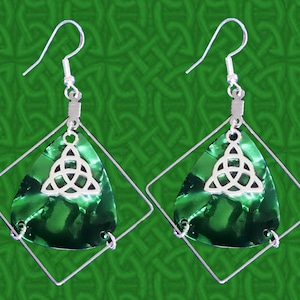 May include: A pair of silver-toned earrings featuring a green, teardrop-shaped pendant within a square frame. Each pendant has a silver Celtic knot charm. The earrings have a hook closure and are set against a green background.