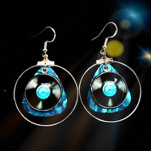 May include: A pair of silver hoop earrings with a blue and black guitar pick pendant. The pick has a small record inside.