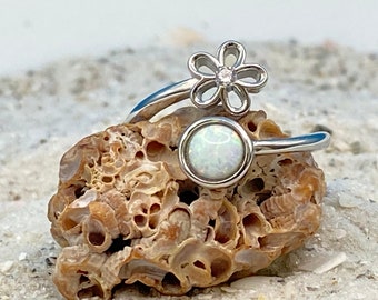 May include: Two silver rings with white opal stones. One ring features a delicate flower design with a small clear stone in the center.