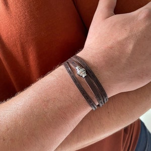 May include: A brown leather bracelet with the words "In faith we forgive those who have wronged us. Amen." and "Will be done, on earth as it is in heaven." engraved on it.