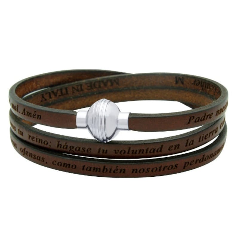 May include: Brown leather wrap bracelet with a silver magnetic clasp. The bracelet has the text "Leather M" and "MADE IN ITALY" on one side and the text "Padre nuestro" and "tu reino; hagase tu voluntad en la tierra" on the other side.