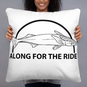 Puede incluir: Cojín cuadrado blanco con un dibujo lineal negro de un pez dentro de un arco negro. El texto "ALONG FOR THE RIDE" está impreso en negro debajo.