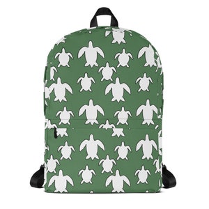 May include: Green backpack featuring a white turtle pattern. The bag has a black handle, black shoulder straps, and a front pocket. The turtle design is repeated across the entire surface of the backpack.