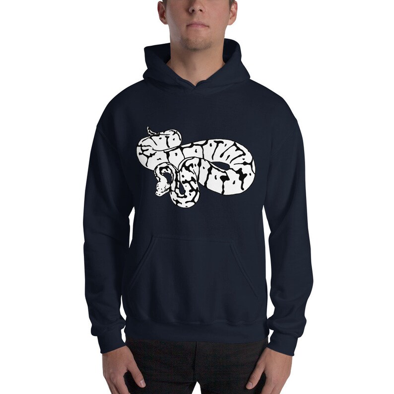 May include: Navy blue hoodie featuring a white graphic of a coiled snake. The snake design has black and white markings. The hoodie has a front pocket and a hood with drawstrings. The model is wearing the hoodie.