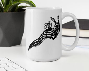 May include: White ceramic mug featuring a black and white illustration of a sea slug. The design is a stylized, detailed drawing of the marine creature. The mug has a standard handle and is suitable for hot or cold beverages.