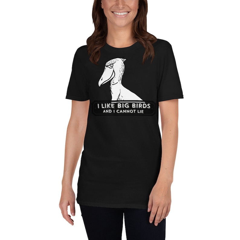 May include: Black t-shirt featuring a Shoebill stork illustration in white. The text "I LIKE BIG BIRDS AND I CANNOT LIE" is printed below the bird. The shirt is a short-sleeved crew neck.