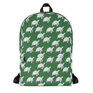 May include: A green backpack featuring a repeating pattern of white turtle illustrations. The backpack has black straps, a top handle, and a front pocket. This bag is a stylish way to carry books, supplies, or personal items.