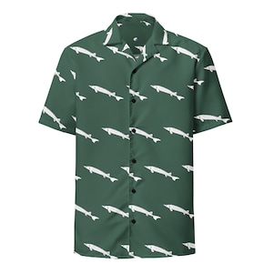 Può includere: Camicia a maniche corte verde scuro con un motivo ripetuto di pesci storione bianchi. La camicia ha un colletto classico e bottoni neri.