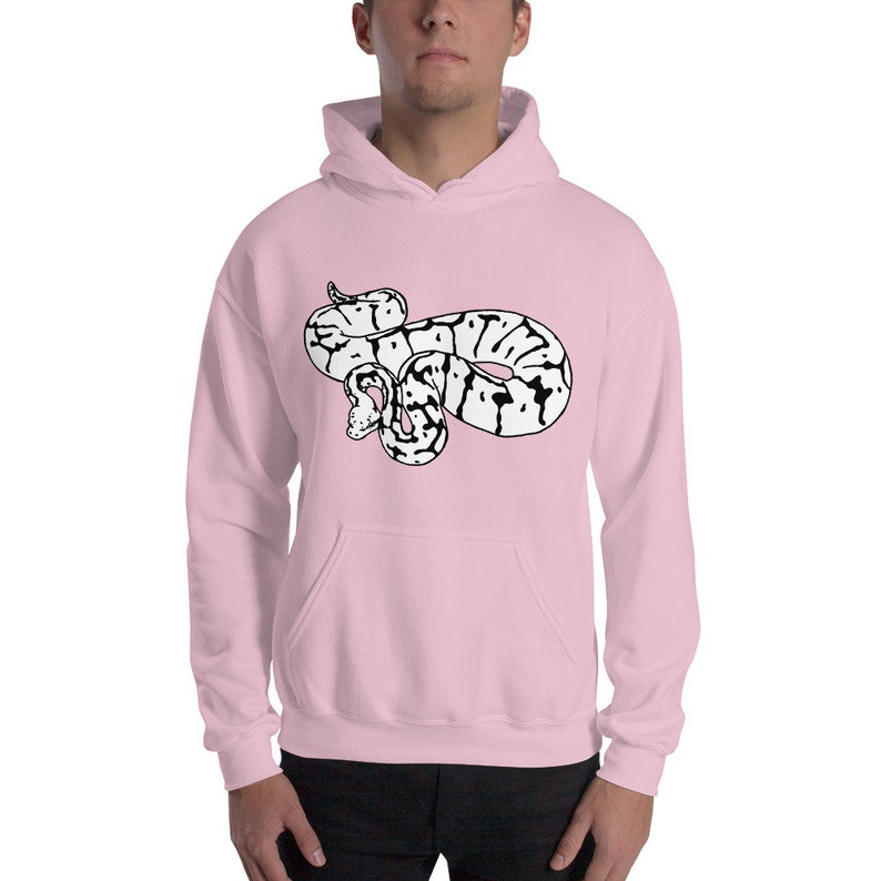 May include: A light pink hooded sweatshirt featuring a black and white snake graphic on the front. The snake is coiled and has a detailed pattern. The sweatshirt has a kangaroo pocket and a drawstring hood.