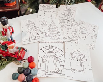 May include: A set of six black and white coloring pages featuring winter holiday themes. The pages include a snowman, a penguin in an igloo, a Christmas tree, a gingerbread man, a nutcracker, and a stocking. The pages are surrounded by colorful play dough.
