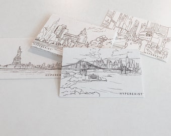 Puede incluir: Cuatro dibujos en blanco y negro de monumentos de Nueva York en tarjetas blancas. Los monumentos incluyen la Estatua de la Libertad, el puente de Brooklyn, el Empire State Building y el Chrysler Building. Cada tarjeta tiene el texto "HYPEREXIST" impreso en la parte inferior.
