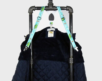 May include: A navy blue quilted jacket hanging on a black metal pipe rack with two blue and green straps. The jacket has a soft, fuzzy lining.