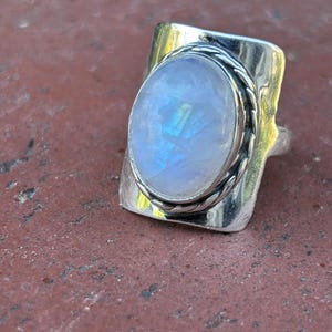 Puede incluir: Un anillo de plata con una gran piedra de luna ovalada engastada en una banda de plata texturizada.
