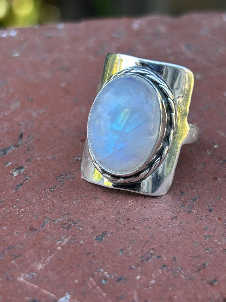 Puede incluir: Un anillo de plata con una gran piedra de luna ovalada engastada en una banda de plata texturizada.