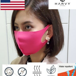 May include: A pink face mask with a cutout for the nose. The mask is made of a breathable material and is water repellent. The mask is being worn by a person with brown hair. The mask has the text "HARVY APPAREL" on the top right corner of the image.