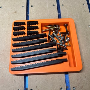 May include: An orange plastic tray with a compartment for small parts. The tray contains black plastic pieces and a variety of screws and bolts.