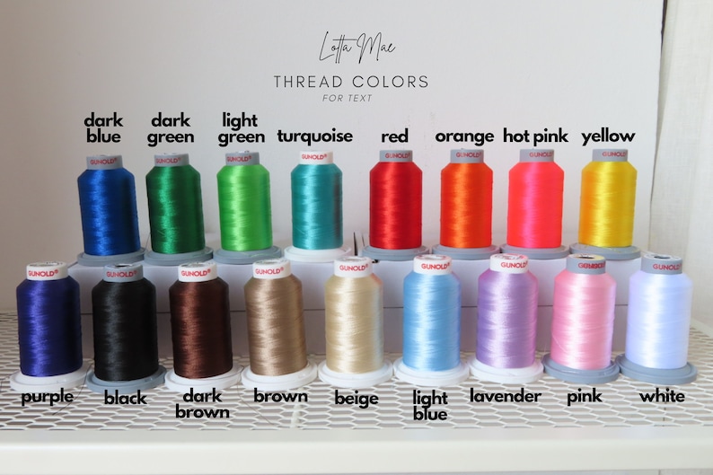 May include: A collection of spools of embroidery thread in various colors, including dark blue, dark green, light green, turquoise, red, orange, hot pink, yellow, purple, black, dark brown, brown, beige, light blue, lavender, pink, and white. The spools are arranged in two rows on a white shelf with a metal grid.