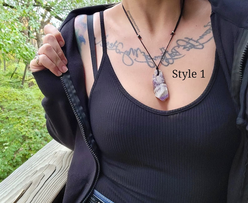 Peut inclure: Un d&eacute;bardeur noir c&ocirc;tel&eacute; avec une veste noire et un collier pendentif. Le collier pr&eacute;sente un grand pendentif en cristal rectangulaire violet et blanc sur un cordon noir. Le texte "Style 1" est visible.
