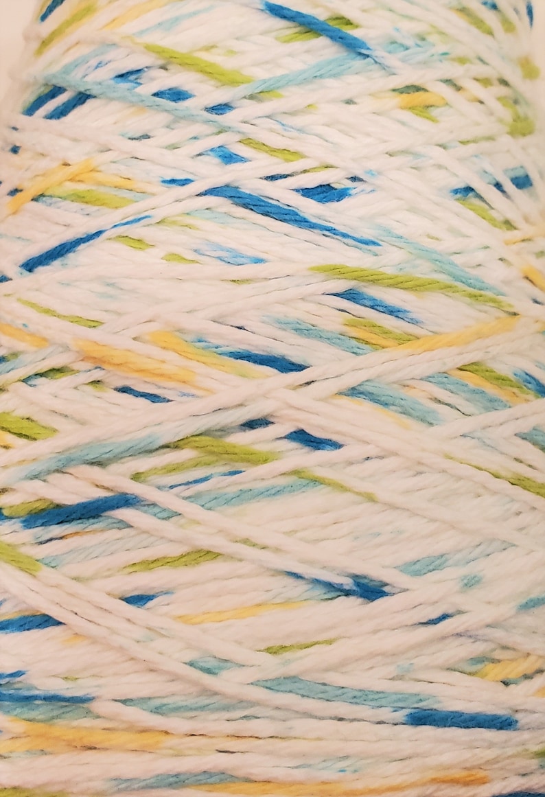 May include: A skein of white yarn with blue, yellow, and green stripes. The yarn is wound into a ball shape.