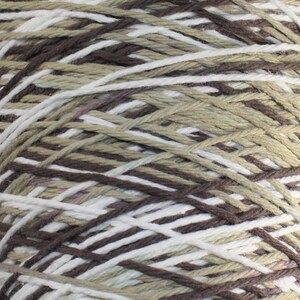 Op de afbeelding: Een bol garen met bruine, witte en beige strepen. Het garen is gemaakt van katoen en is perfect om te breien of te haken.