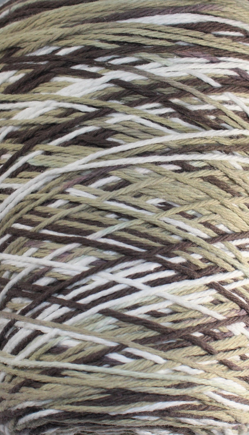 May include: A skein of yarn with brown, white, and beige stripes. The yarn is made of cotton and is perfect for knitting or crocheting.
