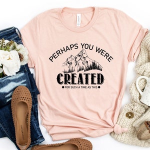 May include: A pink t-shirt with a black mountain graphic and the text "Perhaps you were created for such a time as this".