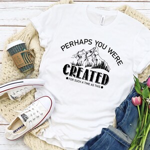 May include: White t-shirt with black text that reads "Perhaps you were created for such a time as this."  The text is surrounded by a graphic of mountains and trees.