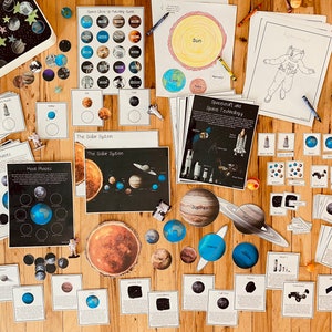May include: A collection of educational resources for learning about space, including posters, flashcards, and manipulatives. The materials feature images of planets, stars, astronauts, and spacecraft. The text on the materials includes the words "Moon Phases", "The Solar System", "Spacecraft and Space Technology", and "Jupiter".