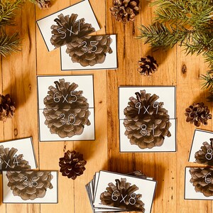 Può includere: Un set di 10 flash card di moltiplicazione stampabili con pigne che mostrano problemi di moltiplicazione e risposte. Le carte sono progettate per aiutare i bambini a imparare le loro tabelline.