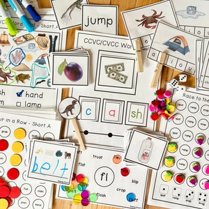 Puede incluir: Un conjunto de tarjetas educativas para niños que aprenden fonética. Las tarjetas presentan ilustraciones coloridas y palabras como "jump", "cash", "clam", "hand", "lamp", "belt", "trust", "flex", "fl", "blip", "crop", "clash", "flash", "fluff", "chop", "shop", "stop", "spot", "ramp", "snap", "brag", "flat", "chat", y "that".
