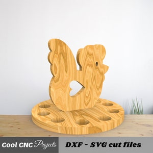 K&ouml;nnte beinhalten: Eierhalter aus Holz in Form eines Huhns mit sechs L&ouml;chern f&uuml;r Eier. Das Huhn steht auf einem runden Sockel. Sockel und Huhn sind aus Naturholz.