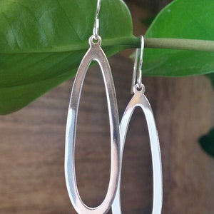 May include: A pair of silver oval hoop earrings with a smooth, polished finish.