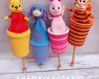 May include: Four crocheted finger puppets, Winnie the Pooh, Piglet, Eeyore, and Tigger, are attached to wooden sticks and placed in crocheted cups. The cups are yellow, blue, pink, and orange with white stripes.