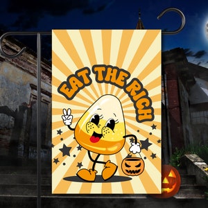 Può includere: Una bandiera da giardino a tema Halloween con un personaggio di mais dolce dei cartoni animati che tiene un secchiello per dolcetto o scherzetto. La bandiera ha uno sfondo a strisce giallo e arancione con il testo "Eat the Rich" in un font retrò.
