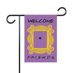 May include: Purple garden flag with a yellow frame with the words "WELCOME" and "FRIENDS" in black text. The frame has a purple background with a black dot in the center.
